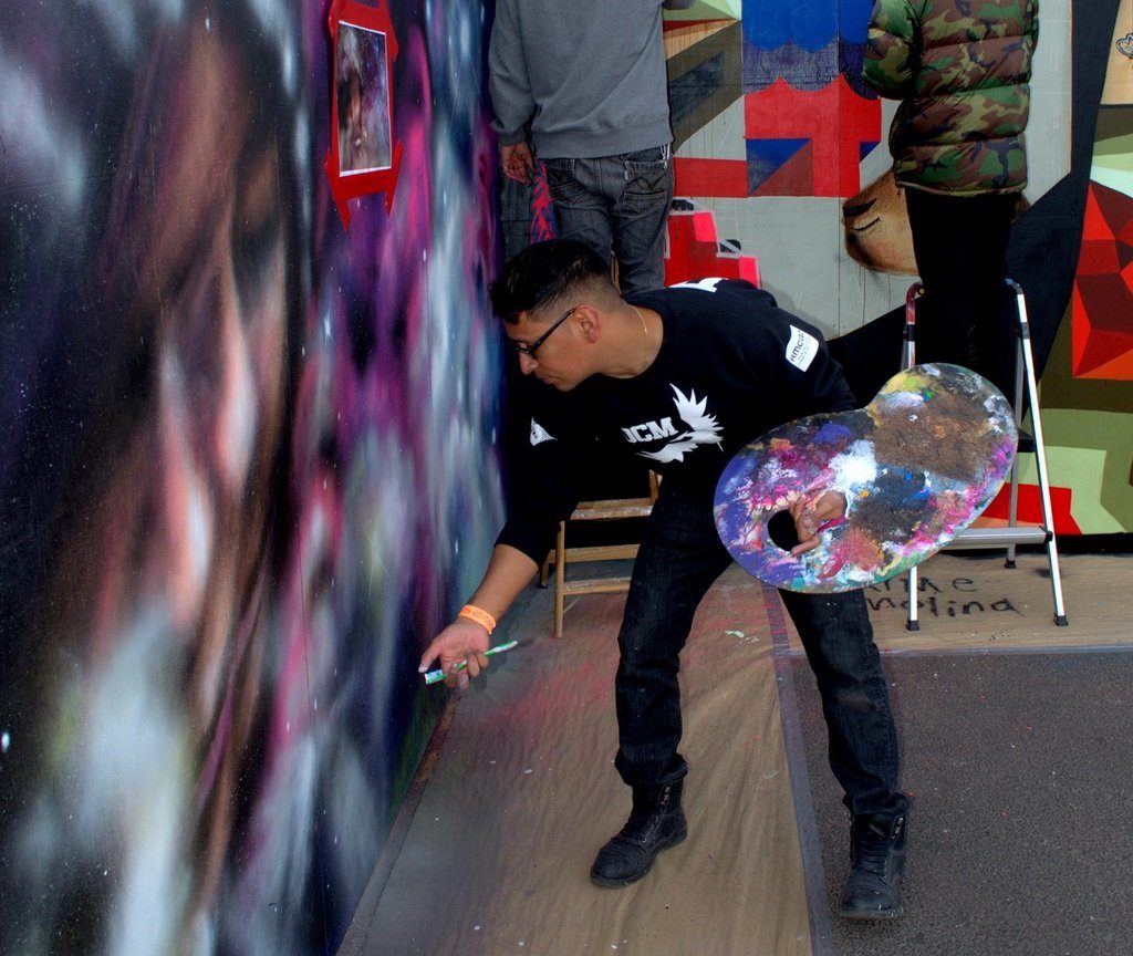 Daniel Chavez working on his mural at Snowball 2014, photo by Lindsey Bartlett.