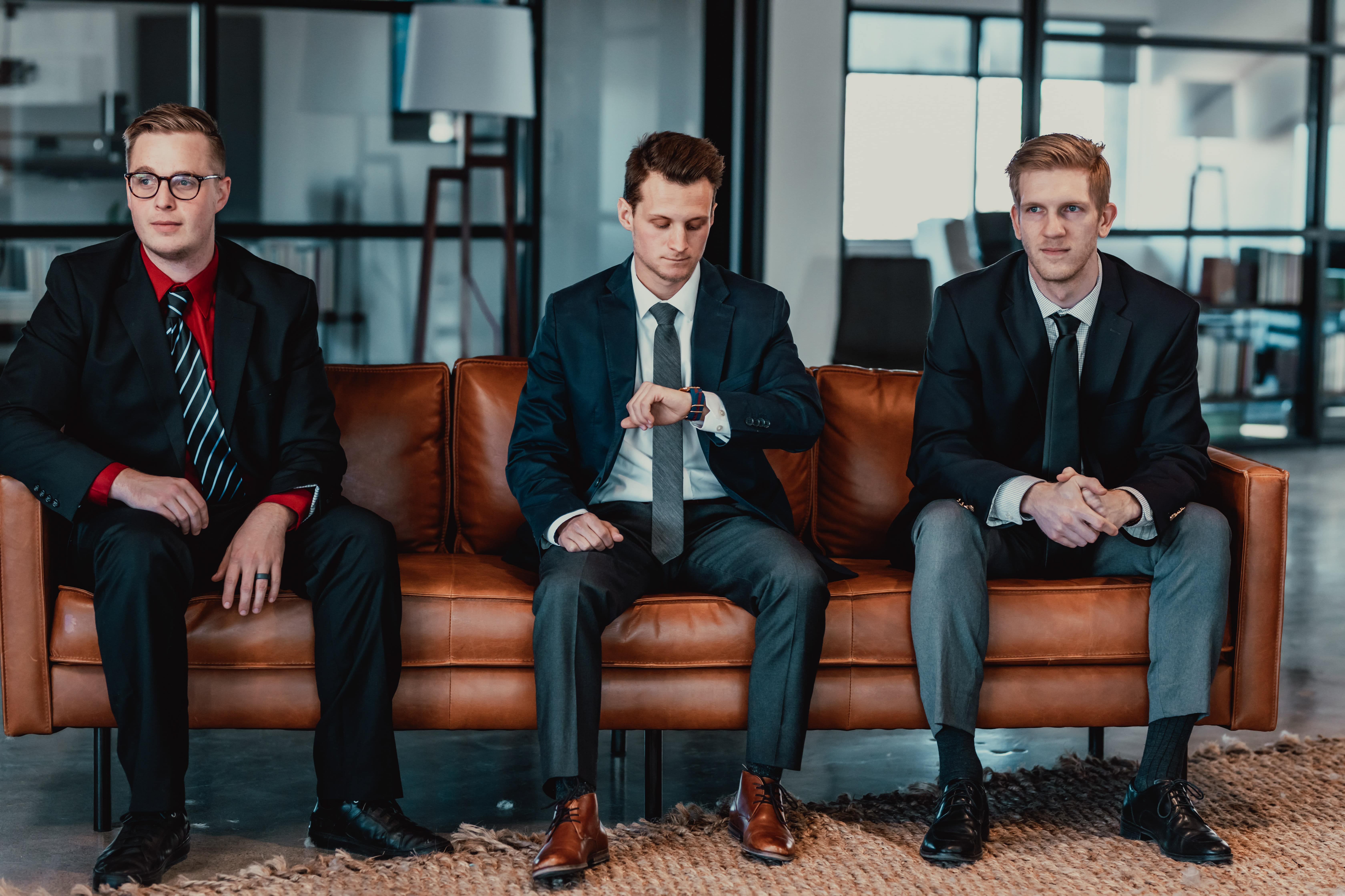 Glass Cases sitting on a couch in business attire