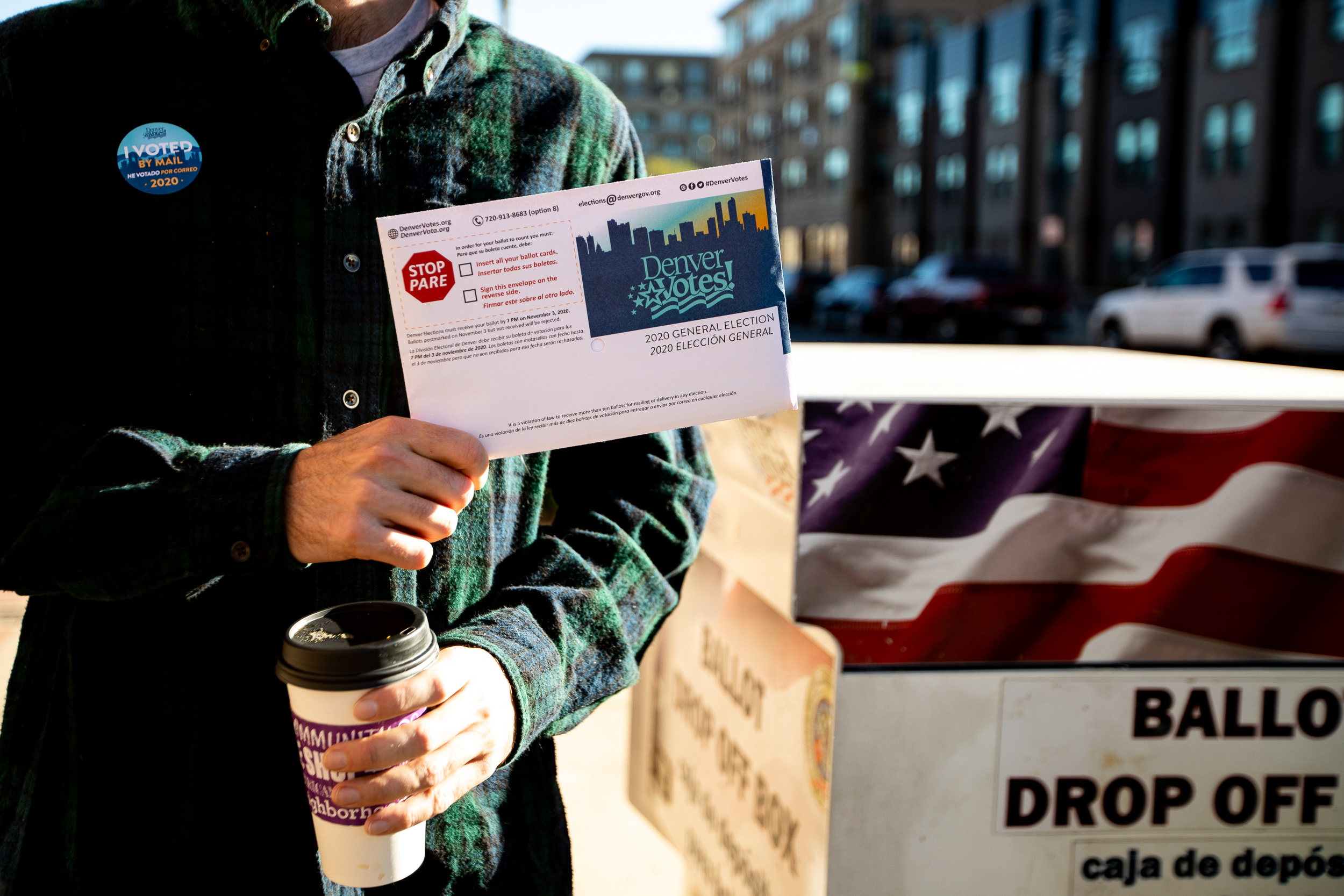 A voter holding their ballot near a Denver ballot dropbox.