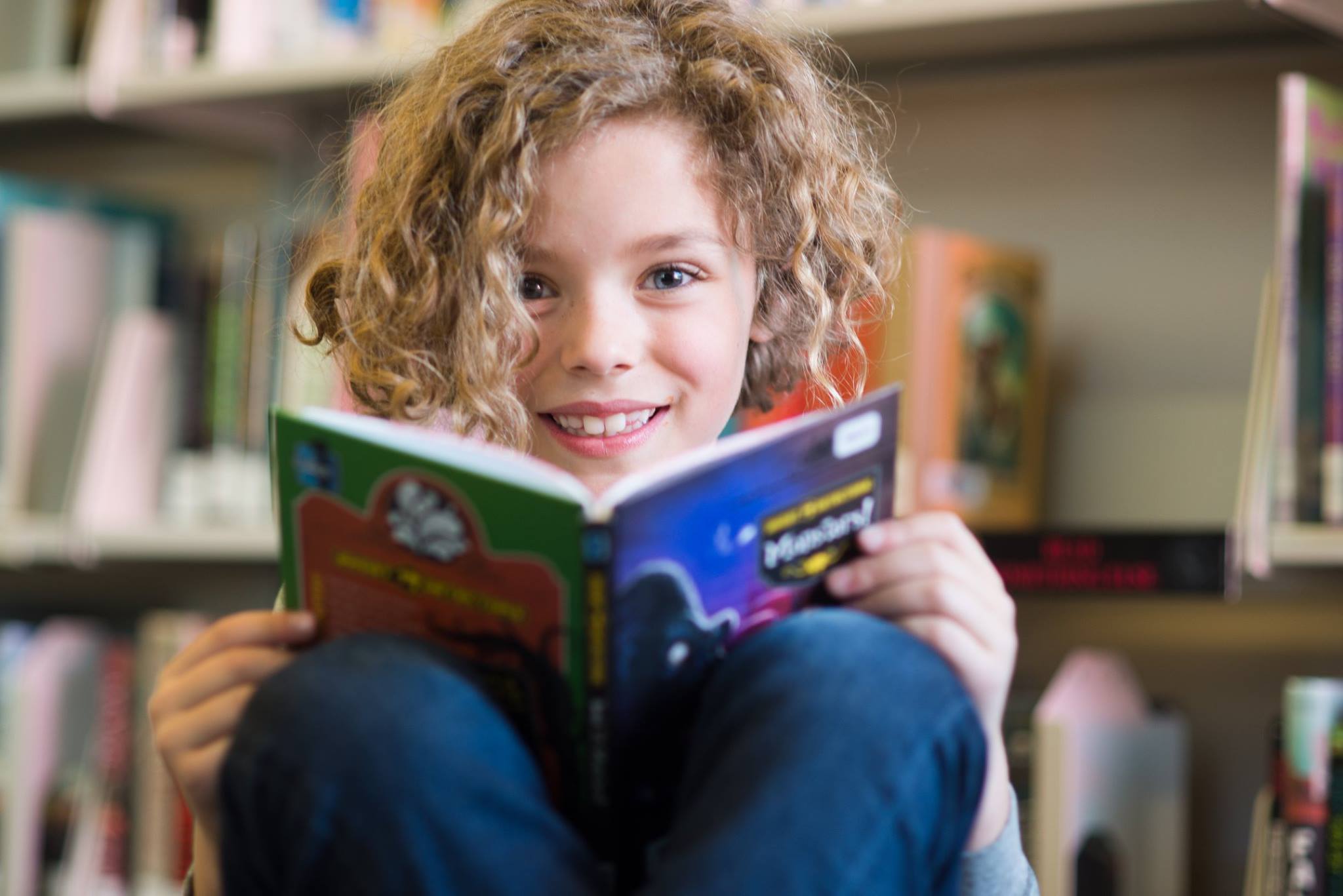 A child smiling and reading a book