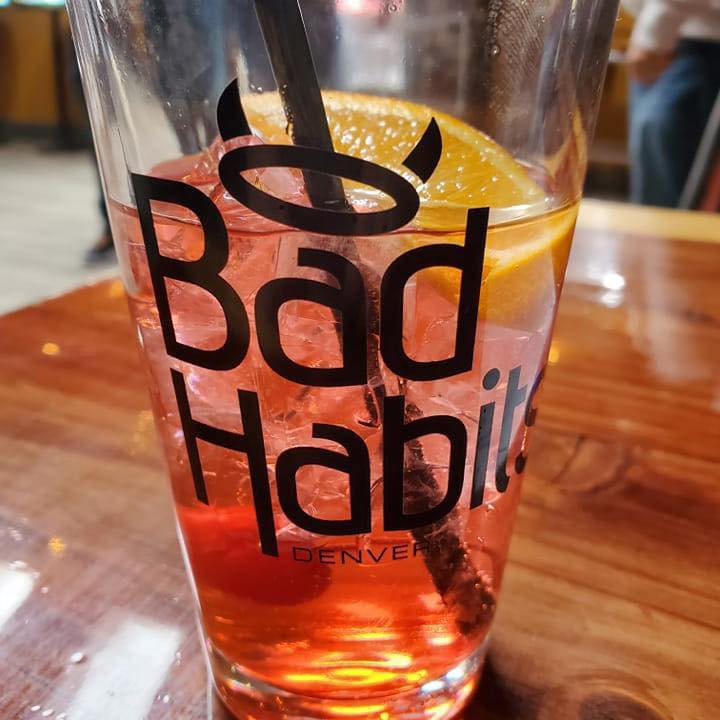 Red drink with orange in Bad Habits glass